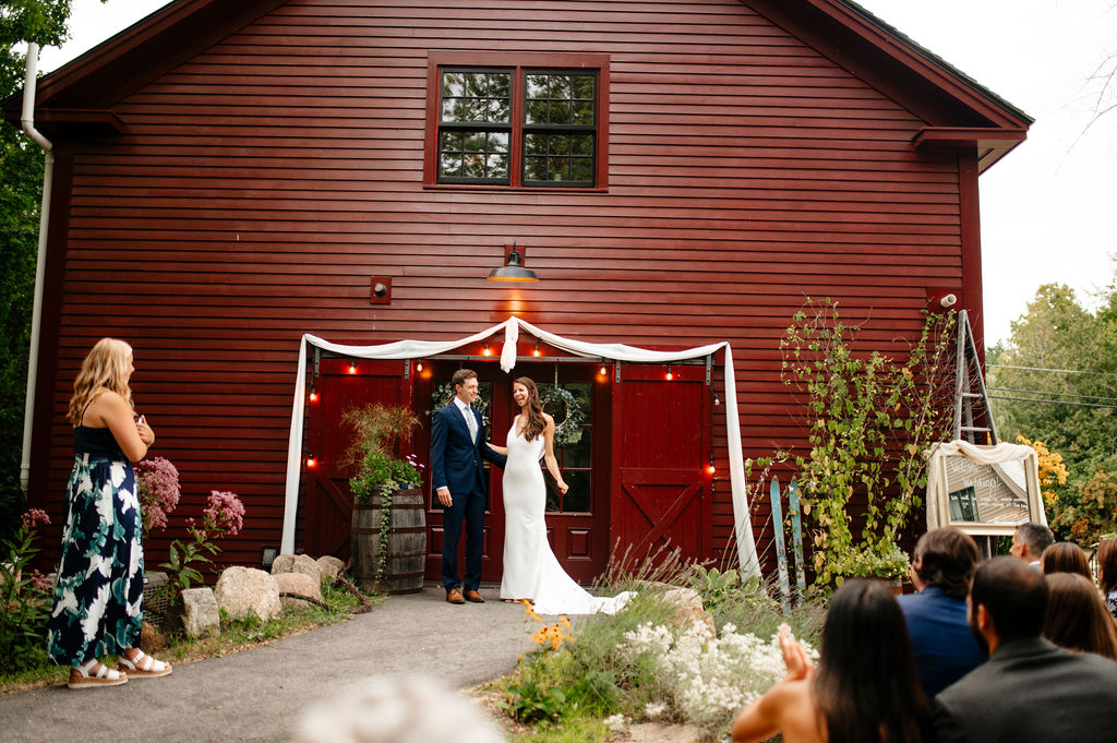 Bride and groom walking toward the red barn venue at Alpine Garden