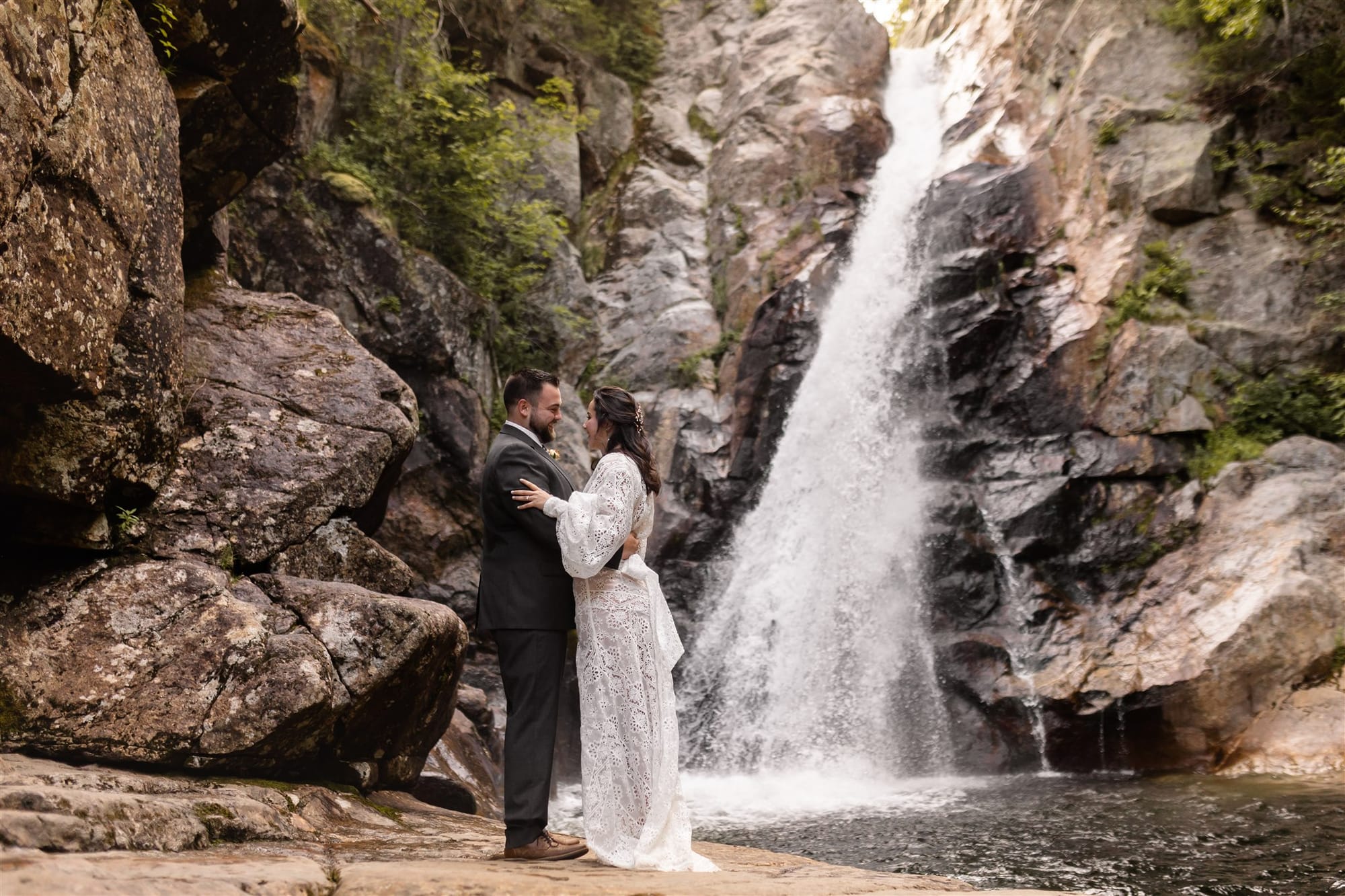 Couple embracing beside a mountain waterfall during their elopement
